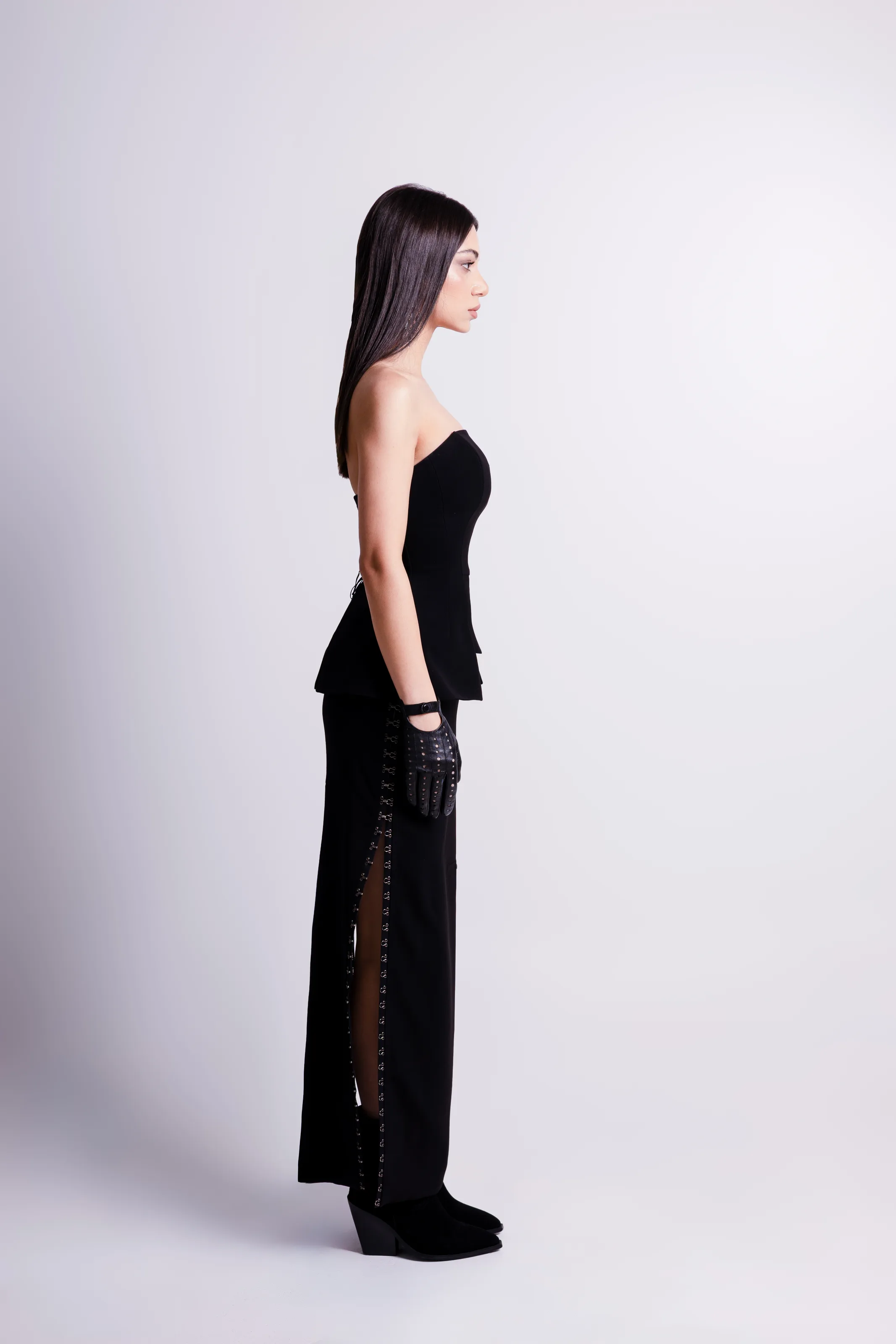 The black strapless look in profile, the slit and its line of silver fastenings running the length of the skirt
