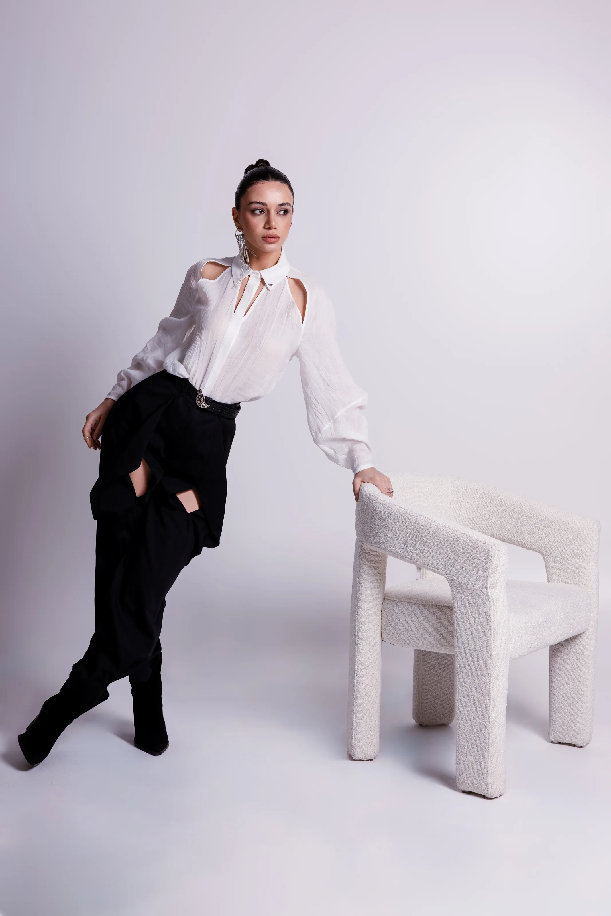 The white cut-out shirt with black trousers belted with an ornamental silver buckle, standing