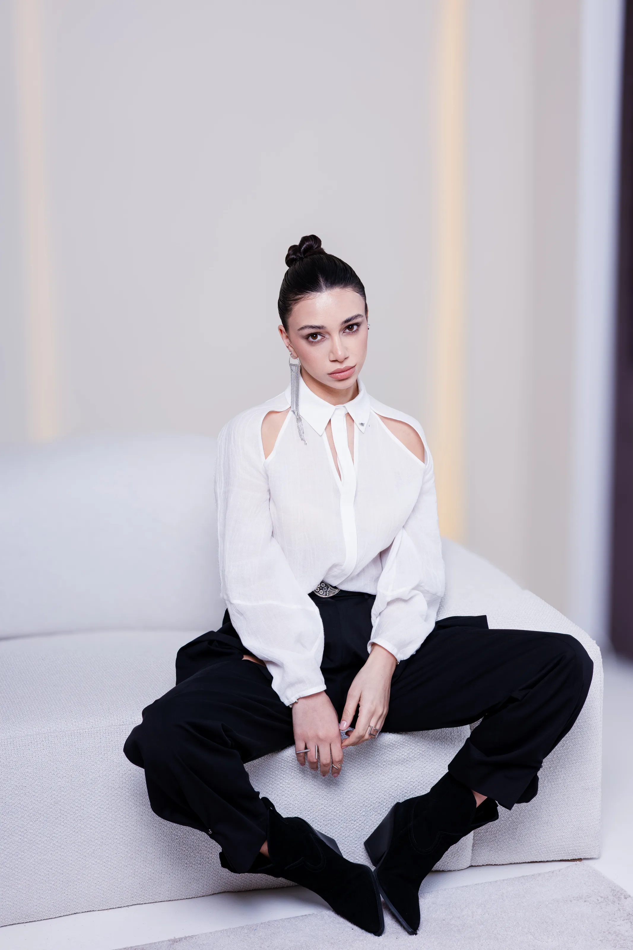 The white cut-out shirt and black trousers seen seated, the shoulder openings and collar in full view
