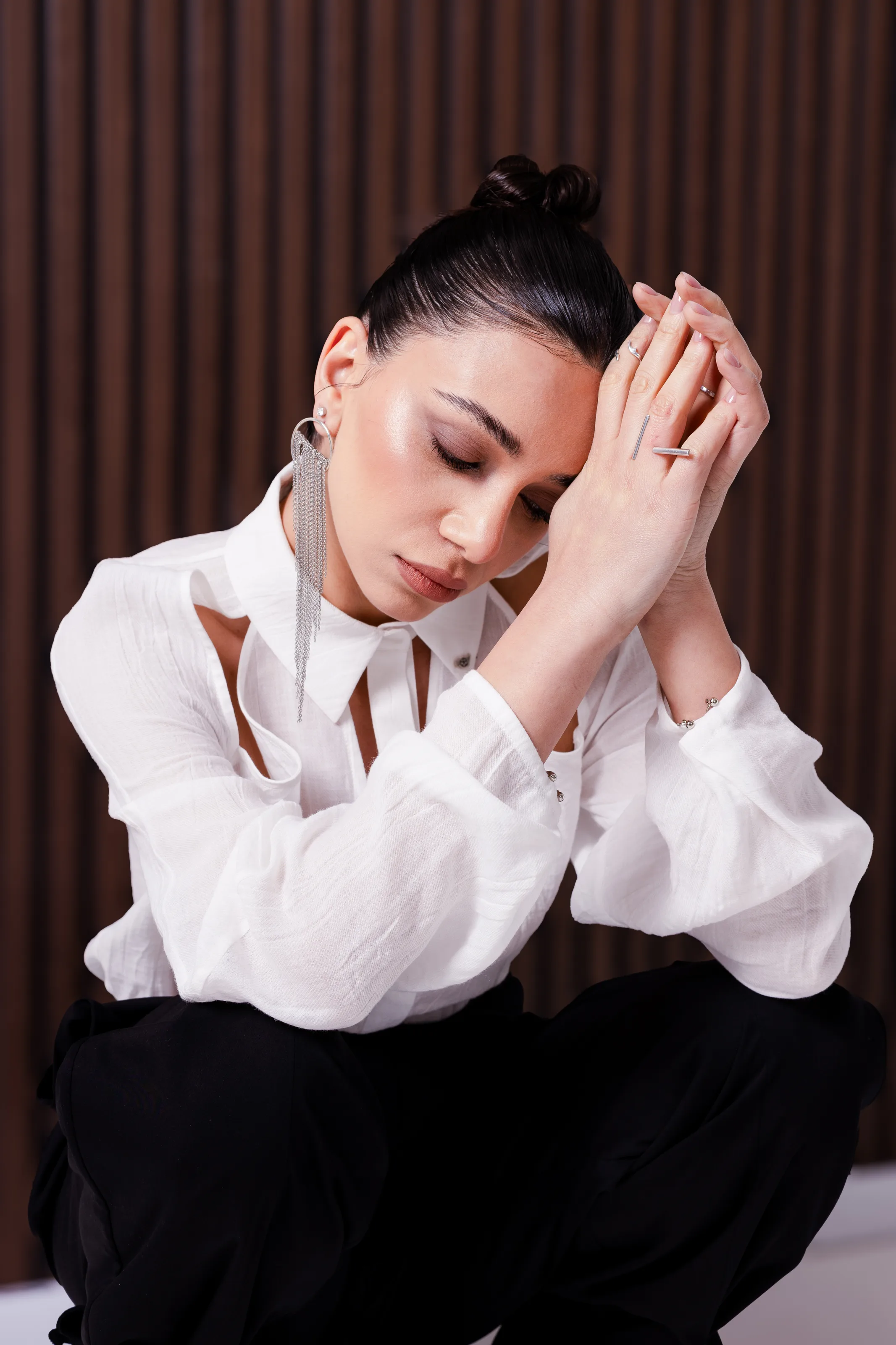 Close portrait of the white cut-out shirt, the collar and shoulder openings against a dark panelled wall
