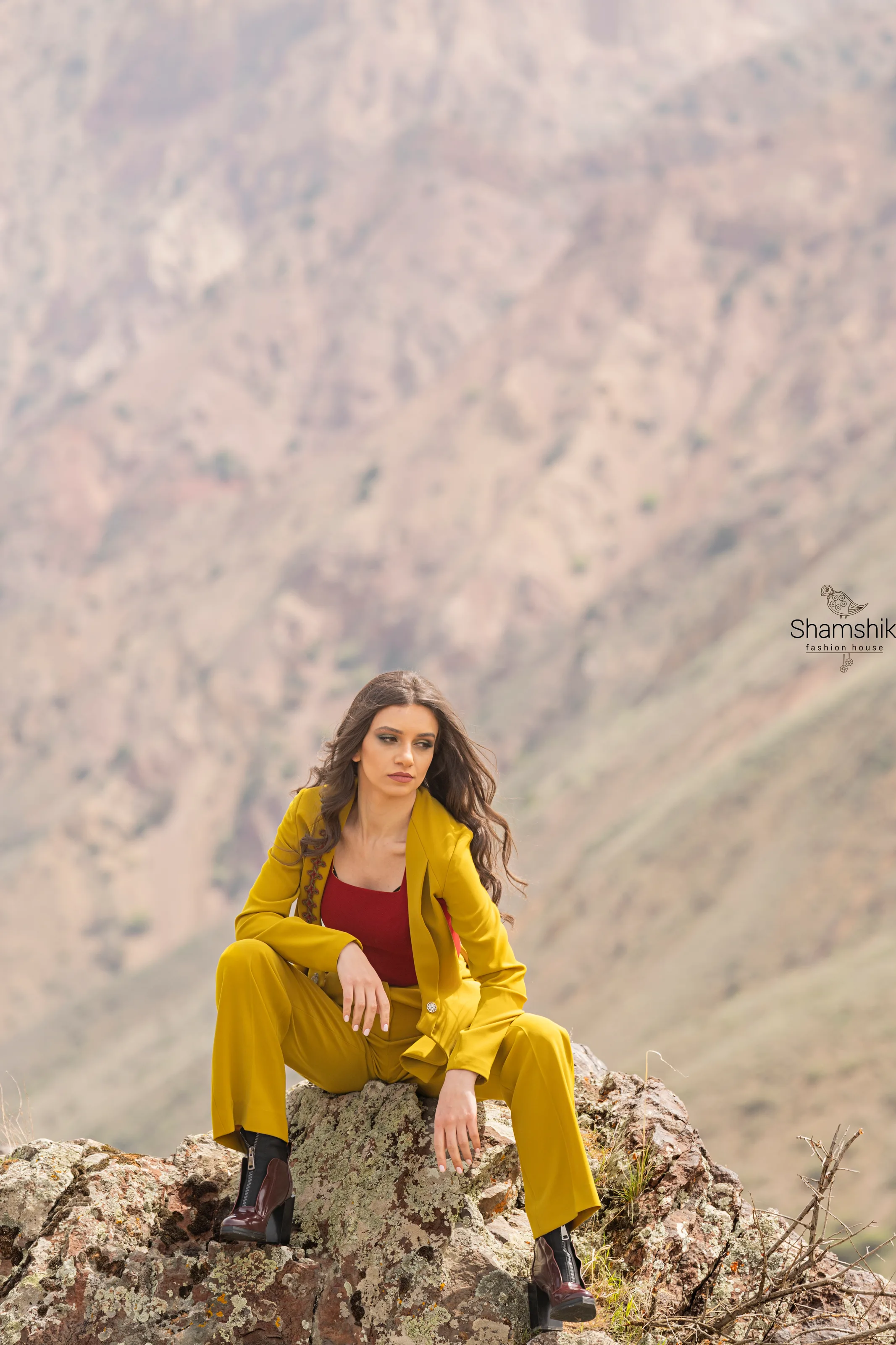 Mustard jacket and wide-leg trousers over a red top, the jacket front edged with rust cord embroidery